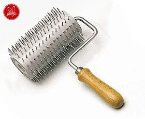 Nålvals med metallnålar och trähandtag, används för att perforera täckvaxet på ljunghonung innan slungning.