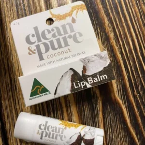 Läppbalsam clean & pure coconut med kokos och naturligt bivax, stift och förpackning på träyta.